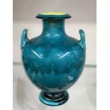 A twin handled art pottery vase, in the style of Burmantofts, Grecian urn form, turquoise with
