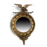 A carved gilt wood convex looking glass, 19th Century, American Federal style eagle pediment, ball
