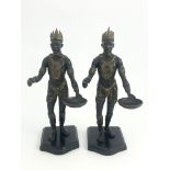 A pair of bronze Nubian warrior figures, modelled wearing crowns and holding trays, highlighted in