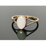 A yellow metal opal single stone ring, the split shank oval setting with line engraved shoulders,