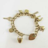 A 9ct yellow gold charm bracelet, the oval links suspending eight various charms and padlock