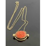 A 9ct gold coral set pendant, with oval floral carved cabochon in closed back collared and curved