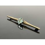 A 9 carat gold and aquamarine bar brooch, the central square cut stone flanked by spear head