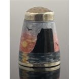 A Norwegian silver and enamelled thimble, KH, decorated in the round with a seascape at sunset