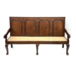 A George III country oak hall settle, circa 1770, quarter fielded panel back, downswept scroll arms,