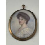 An Edwardian portrait miniature, oval, depicting a dark haired woman in lace shouldered dress,