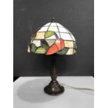 An Art Deco style table lamp with hexagonal panelled geometric leaded glass shade, on faceted