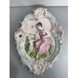 A German tinted bisque cartouche-shaped wall plaque, modelled in high relief with a maiden and