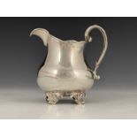 A Victorian silver milk or cream jug, of squat baluster form, with C scroll handle, atop four volute