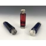 A group of three cut glass and white metal scent bottles, each of cylindrical form with faceted