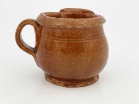 An American redware shaving mug, circa 1850, globular form with lobed spoout and reeded loop handle,