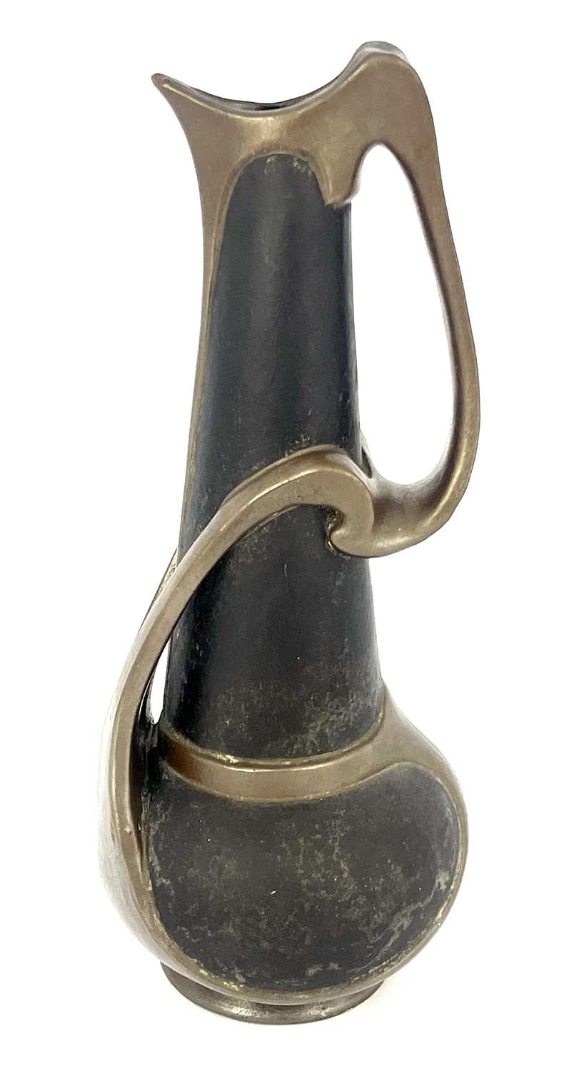 A Bretby Arts and Crafts metallic strap jug, globe and cone form with tendril strap handle, in the