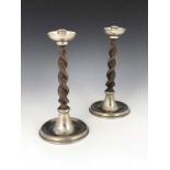 A E Jones, a pair of Arts and Crafts silver plated and turned oak candlesticks, circa 1920, the