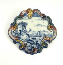 A Dutch Delft polychrome wall plaque, circa 1780, painted with a blue and white Romantic landscape
