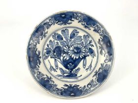 A Delft blue and white dish, painted with a still life of a vase of flowers within a floral