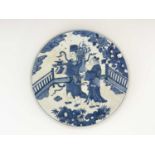 A Chinese blue and white plaque, circular form, painted with two ceremonial figures in a garden