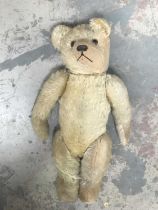 A straw-filled golden plush teddy bear, glass eyes, horizontally stitched nose, jointed limbs, cloth