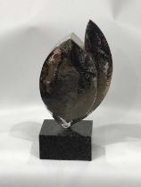A hammered nickel sculpture of double teardrop form, mounted on a granite plinth with a card to