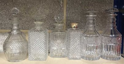 A group of six cut glass decanters with stoppers, including silver mounted hobnail cut spirit