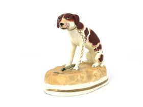 A 19th Century Rockingham-type figure of a brown and white sporting dog, seated wearing a gilt