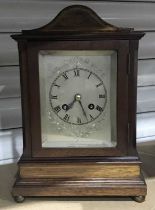 An Edwardian mahogany bracket clock, arched top, silvered dial with Roman numerals, brass ball feet,