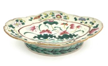 A Chinese famille rose dish, ogee rimmed oval form on cylindrical foot, decorated with flowers