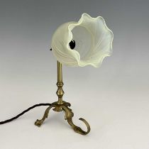 An Arts and Crafts brass Pullman type lamp, with vaseline glass shade, three foliate legs, one