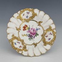 A Meissen dish, relief moulded foliate scroll cartouches highlighted in gilt, with central floral