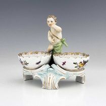 A Berlin porcelain figural double salt cellar, 19th century, the central putto between two basket