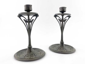A pair of bronze Art Nouveau candlesticks, disc drip-pan on sinuous openwork stem to circular dished