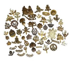 A collection of early 20th century British military cap badges and shoulder titles, including