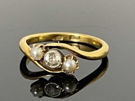 An 18ct gold diamond and pearl set three stone twist ring, the bezel set single diamond flanked by