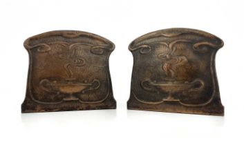 A pair of Arts and Crafts copper bookends, repousse embossed and planished with stylised Roman oil