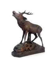 A Black Forest carved wooden model of a stag, standing on a rocky outcrop with head raised, five-