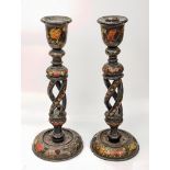 A pair of late 19th/early 20th century lacquered folk candlesticks, red floral splays on a black