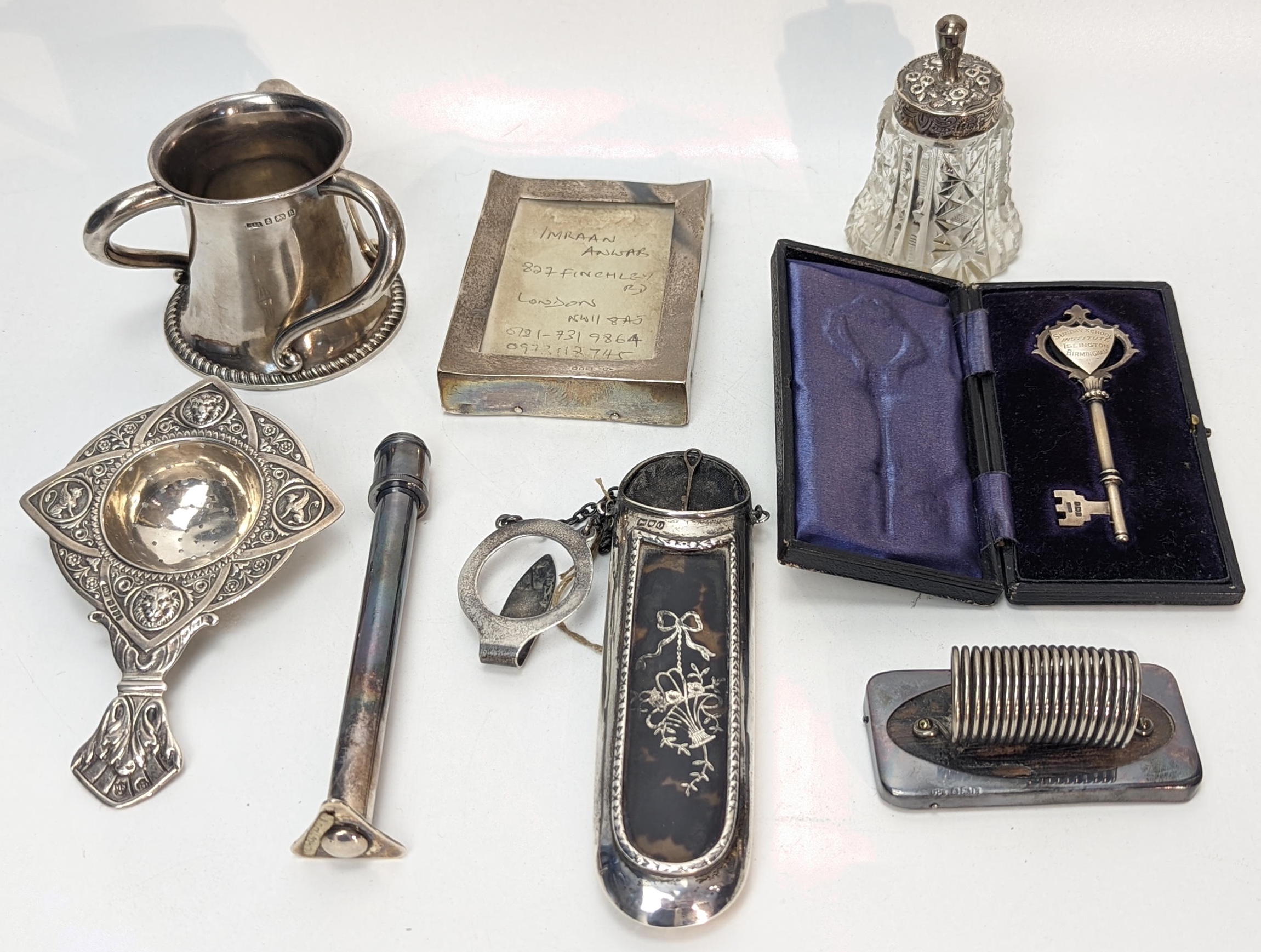 A collection of silver items to include an Arts and Crafts three handled pot, a tea strainer, a