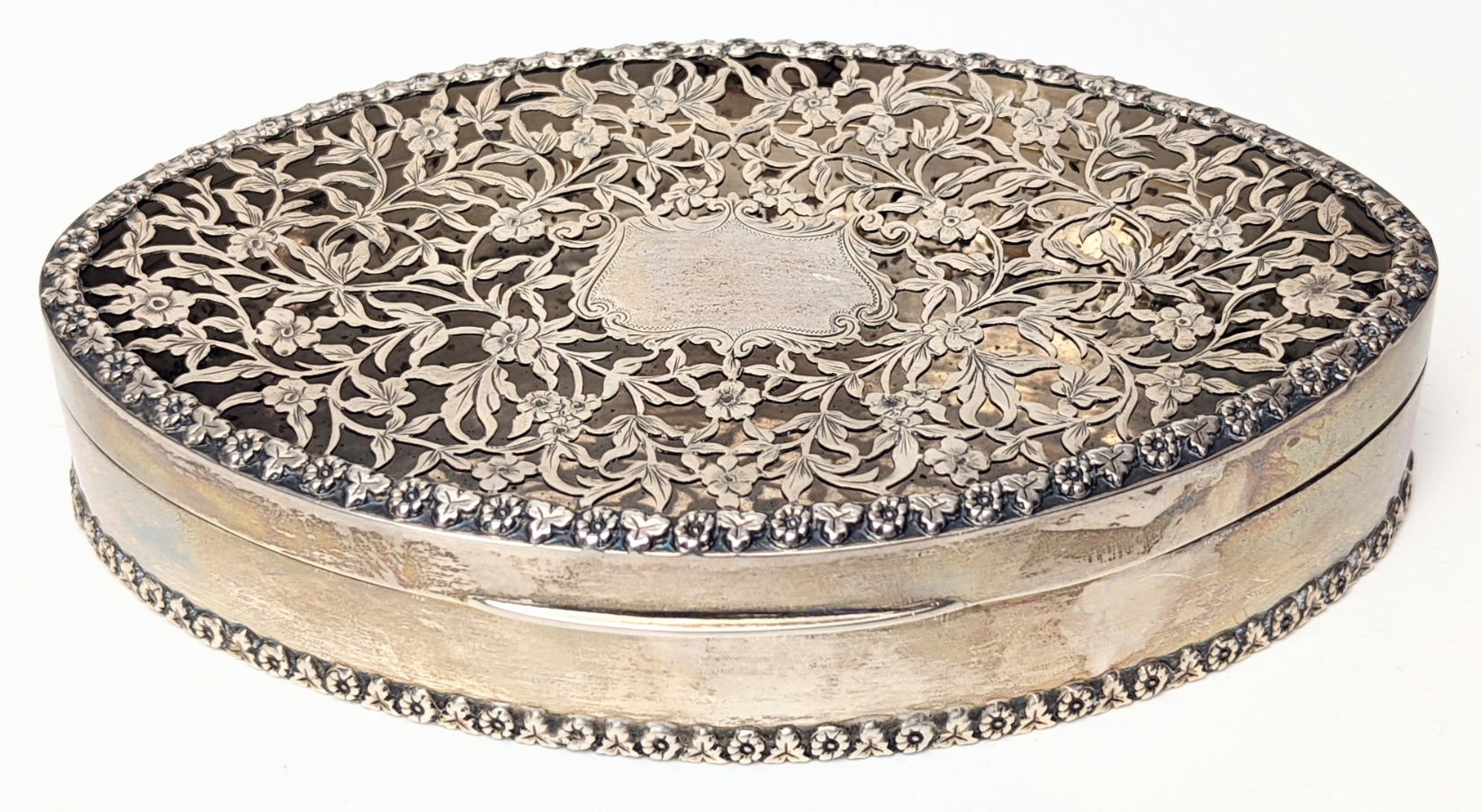 A large Edwardian silver scent box, oval shaped with pierced top, vacant cartouche, hallmarked