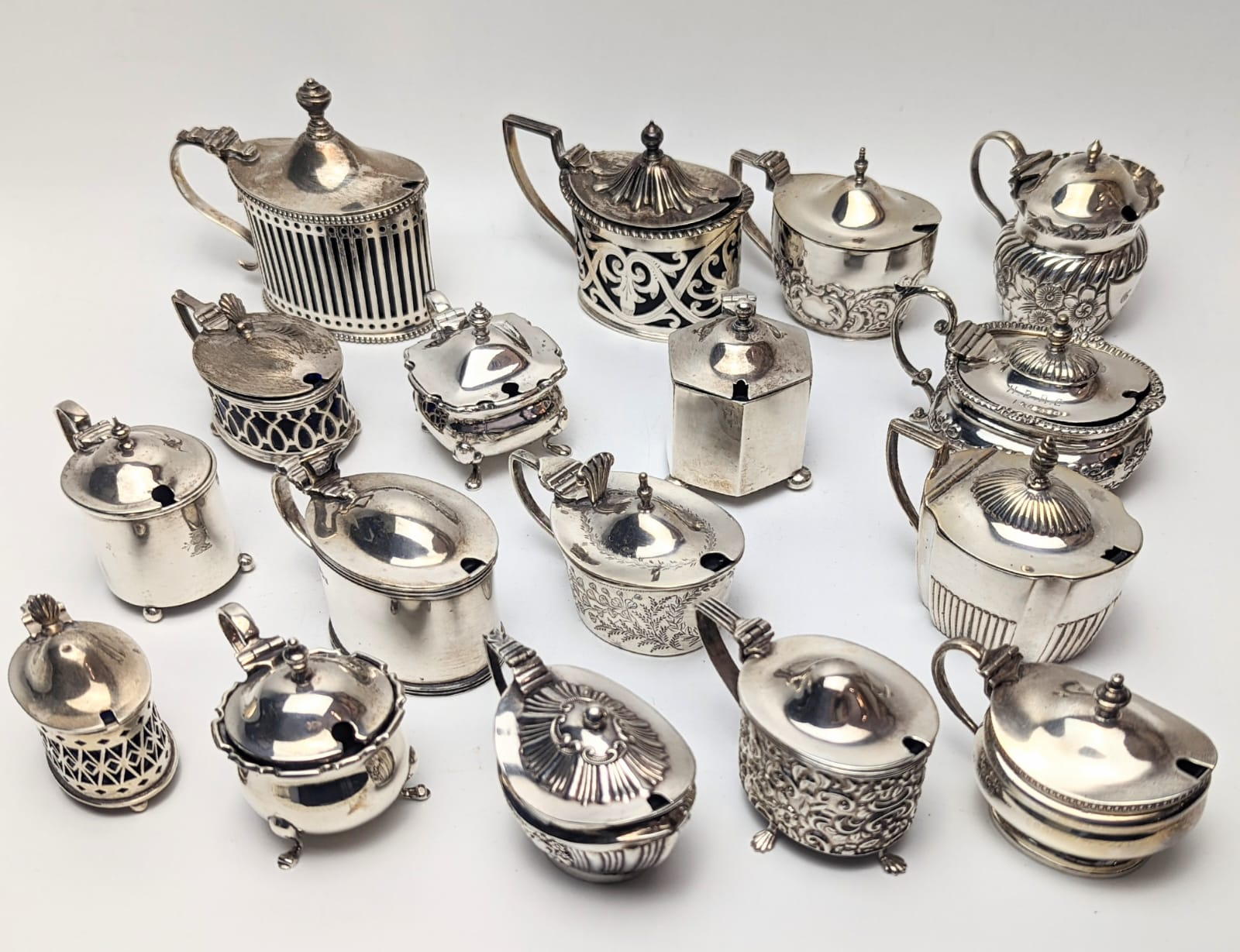 A collection of Edwardian silver mustard pots, British hallmarks, most with glass liners, total