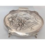 An Art Nouveau silver box, the top depicting Welsh daffodils, raised on four splay feet, velvet