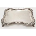 An Edwardian rectangular shaped silver salver, raised on four scrolling feet, hallmarked