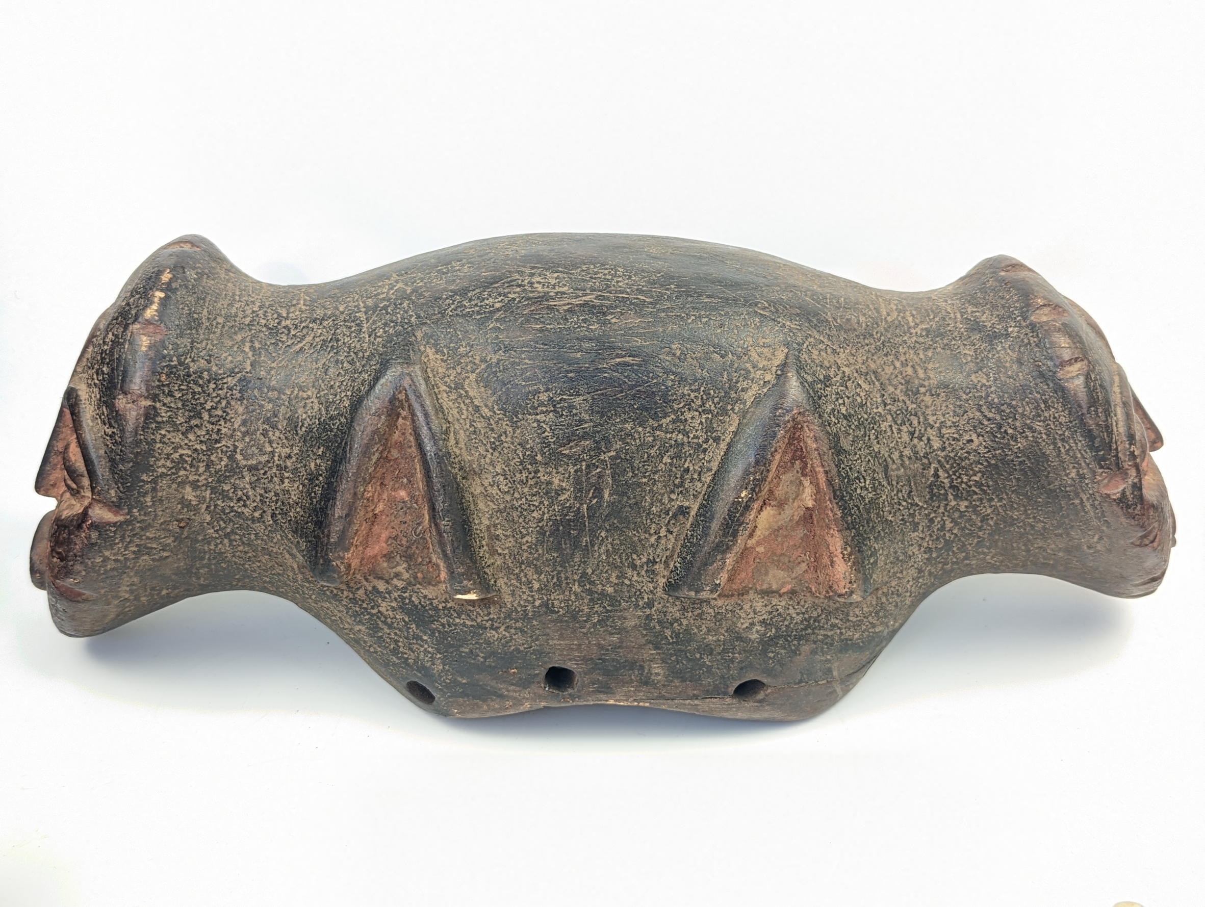 An African tribal Janus helmut, twin face masks on each end, L.39cm