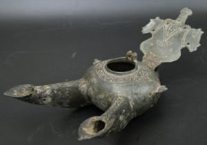 An unusual 13th century Persian Seljuk bronze double spouted oil lamp with a handle on the shape