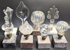 A collection of 8 glass finials mounted on square marble bases