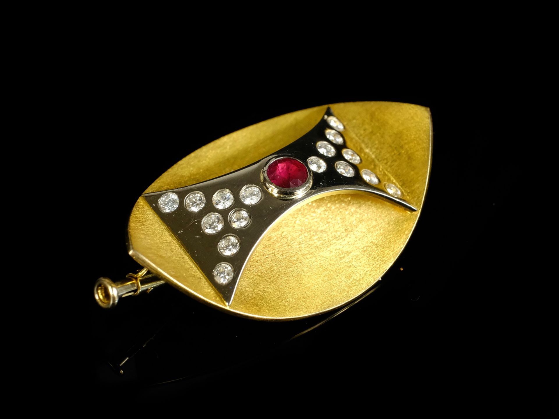 BROOCH bicolour, of concave form with convex applied decoration, this set with round ruby (around 0