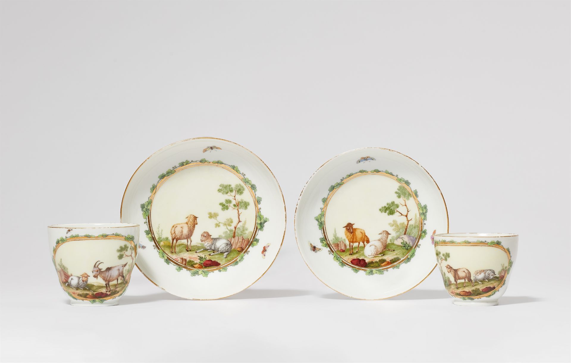 A pair of Berlin KPM porcelain cups and saucers with goats and sheep