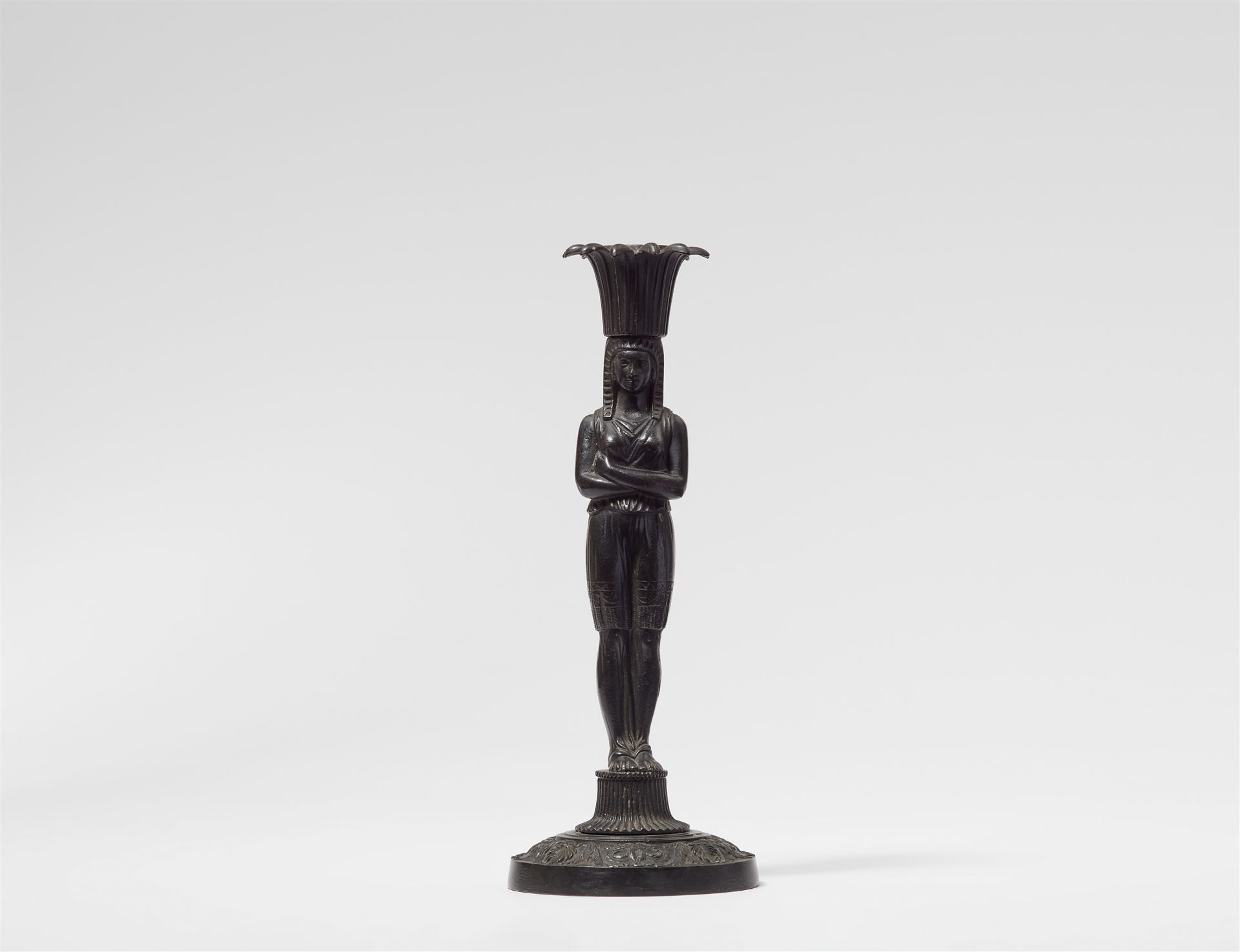 A cast iron candlestick formed as an Egyptian lady