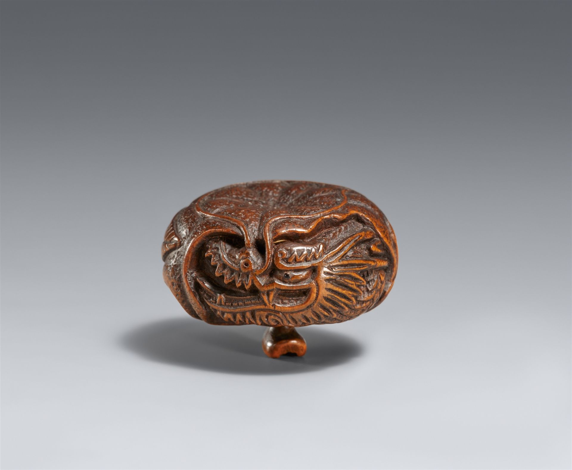 A boxwood netsuke of a dragon inside a mikan. Tanba. Mid-19th century