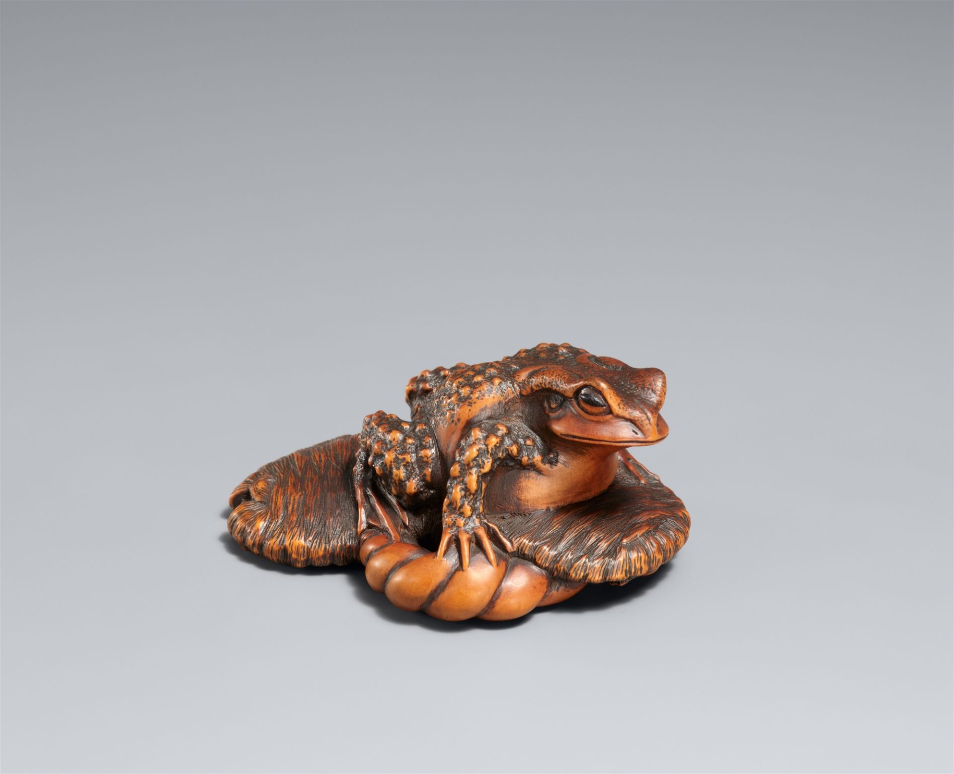 A large boxwood okimono-type netsuke of a toad on a straw sandal. Ise, late 19th century