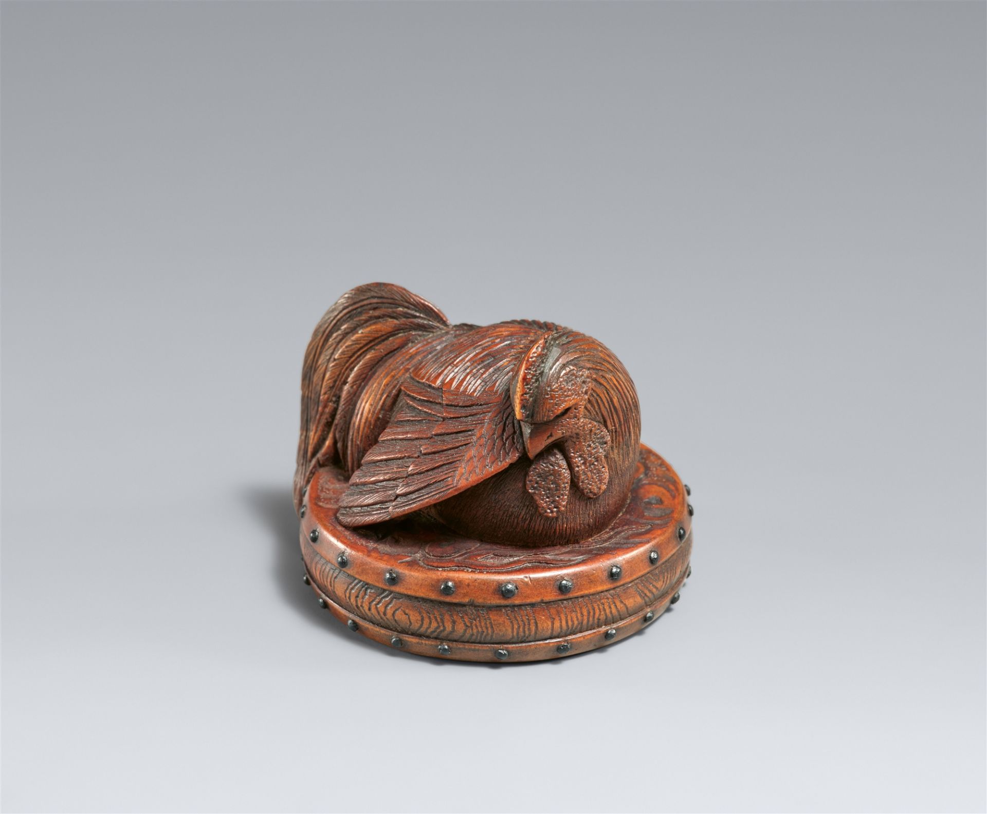 A boxwood netsuke of a large rooster on a flat drum. Second half 19th century