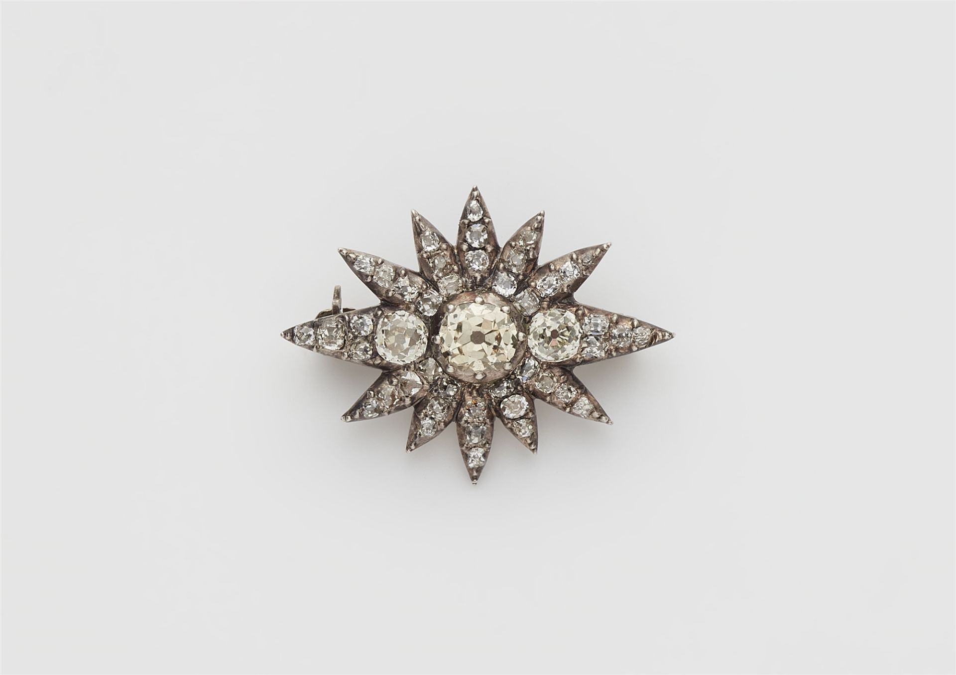 A small silver and cushion-cut diamond star brooch.